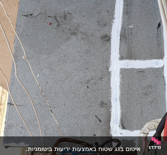 איטום גג עם חומר לבן על יריעה אפורה